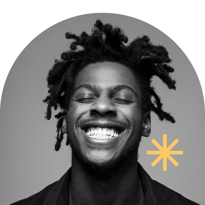 Een jonge man met een brede glimlach en krullend haar, tegen een neutrale achtergrond, met een stervorming accent erbij.
