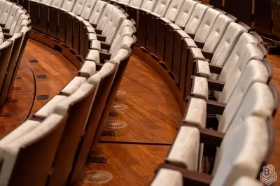 Close-up van gebogen rijen witte theaterstoelen op een houten vloer