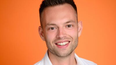 Portret van een man met een glimlach, kort haar, op een achtergrond in een felle oranje kleur.