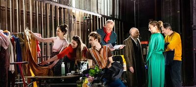 Groep mensen in een theater achter de schermen, bezig met kostuums en decor, met een focus op samenwerking en creatie.