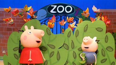 Twee cartoonachtige varkens staan bij een dierenentree met de tekst "ZOO" op een muur. Achtergrond met bladeren en vlinders.