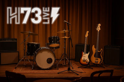 Een podium met een drumstel en twee gitaren, klaar voor een live muziekoptreden, met het logo van H73 Live.