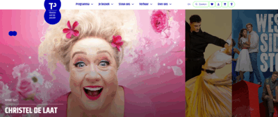 Een blijde vrouw met bloemen in het haar poseert voor een kleurrijke, roze achtergrond.