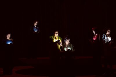 Groep mensen in het donker, alleen verlicht door hun telefoons, met verschillende houdingen en gezichtsuitdrukkingen.