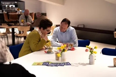 Twee mensen bekijken het programma aan een tafel