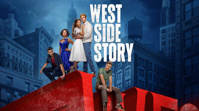 Promotiebeeld van de musical *West Side Story*. Vijf jonge mensen poseren op grote rode letters tegen een achtergrond van hoge stadsgebouwen bij schemering. In het midden staat een stel dicht bij elkaar, terwijl de anderen in verschillende houdingen om hen heen staan. De titel “WEST SIDE STORY” staat groot afgebeeld boven hen.